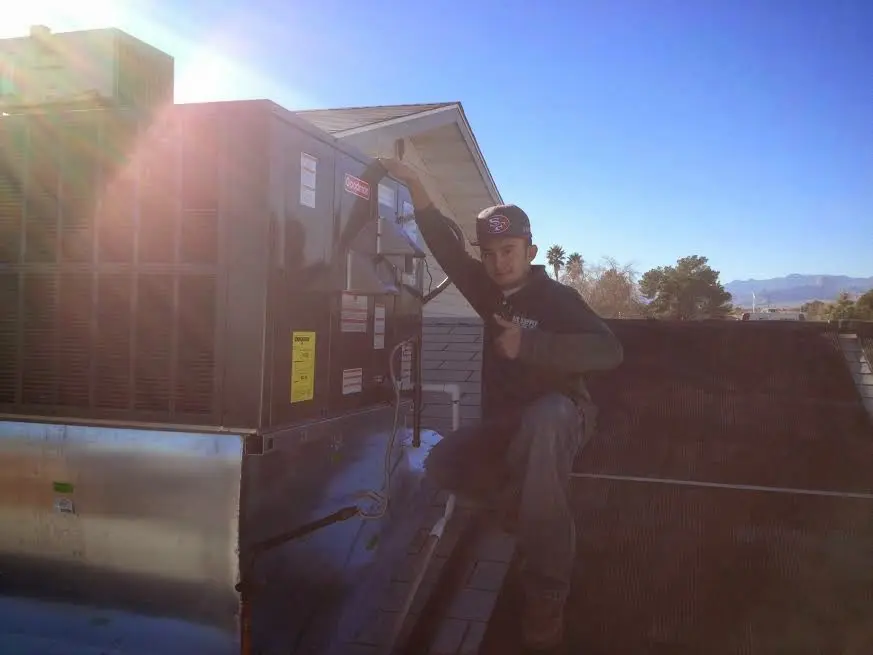 HVAC technician performing Air Duct Cleaning on a rooftop unit in George Mason